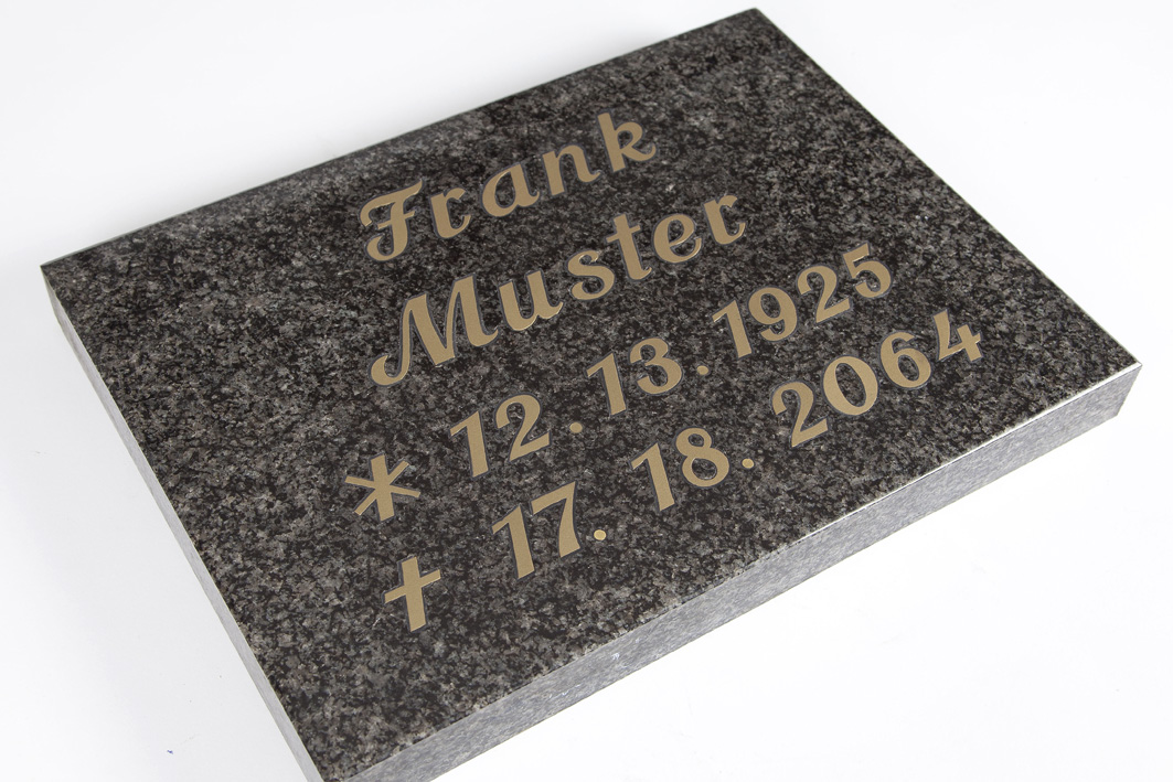 Hochwertige Intarsien-Inschrift aus grauem Granit – Steinmetz Bartels Grau gemusterte Grabtafel mit Intarsien-Inschrift, schräg von oben fotografiert